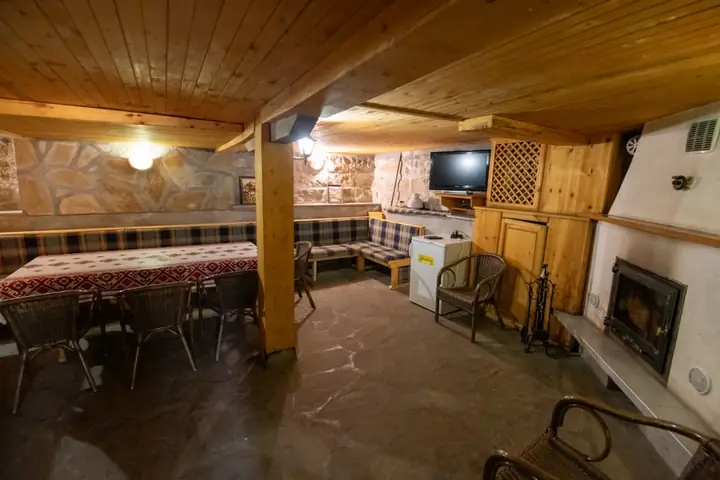 Механата с масата, телевизора и зиданата ниша в каменната стена